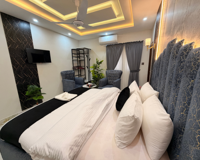 A Hotel Room With A Cozy Bed, A Functional Desk, A Comfortable Chair, A Bright Lamp, And A Stylish Mirror at The Decent Luxury Guest House - 5